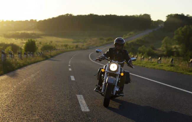 motorcycle3-fp Man riding motorcycle with green hills and tress in the background illustrates blog "Is Motorcycle Insurance Less Expensive Than Car Insurance?"