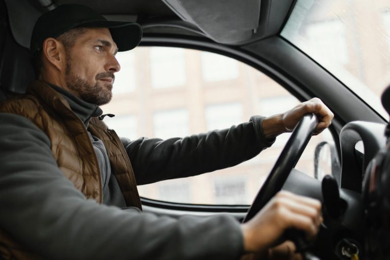 Trucker driving seen from a low angle illustrates blog "Does Commercial Auto Insurance Cover Cargo?"