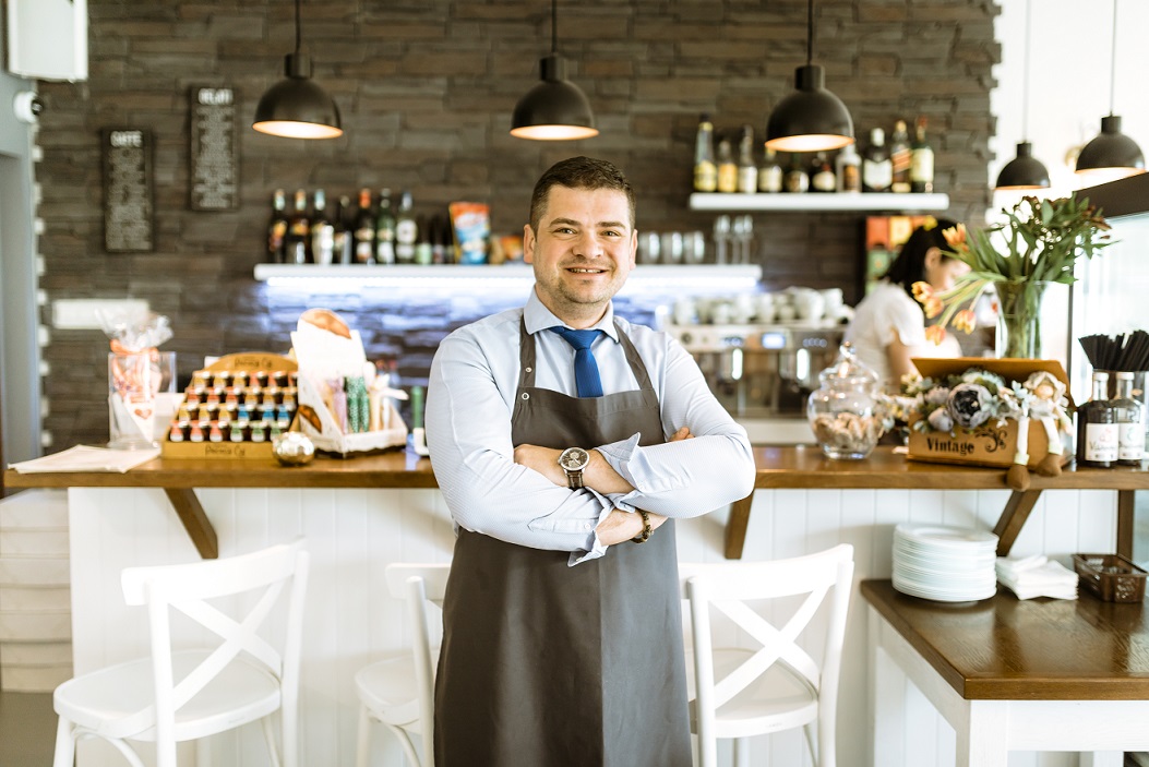 small-business-owner-fp Man with folded arms in small business establishment illustrates blog "Does Commercial Property Insurance Cover Roof Leaks?"