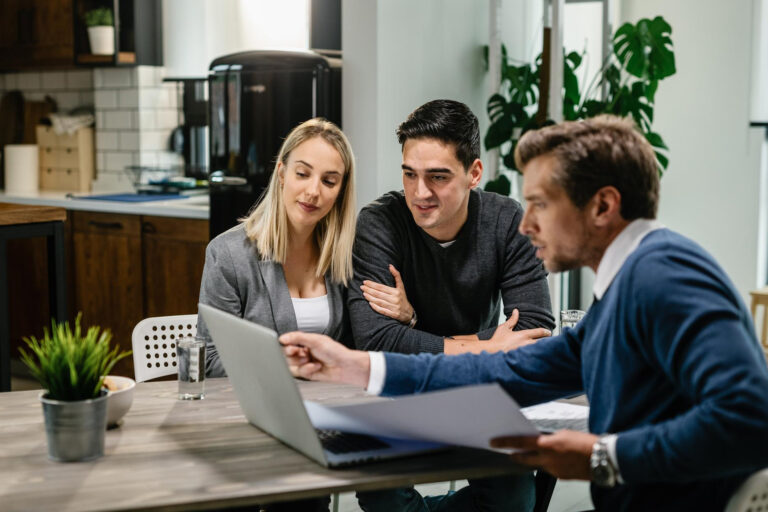 young-couple-real-estate-agent-using-laptop-while-going-through-housing-plan-meeting